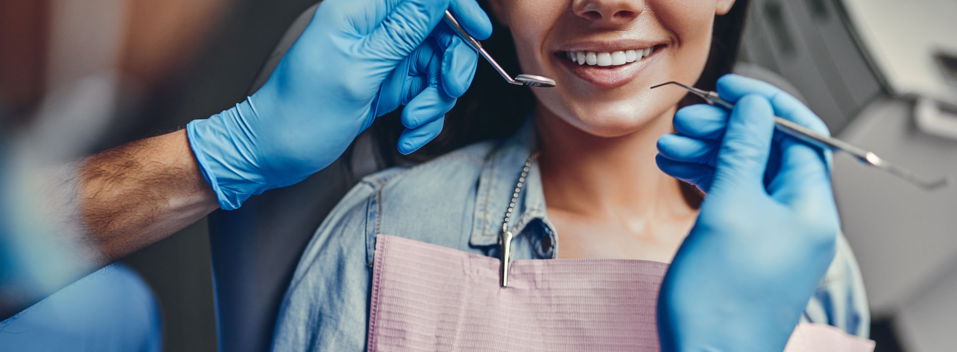 In the image, a person is receiving dental care with a dental hygienist performing a cleaning procedure.