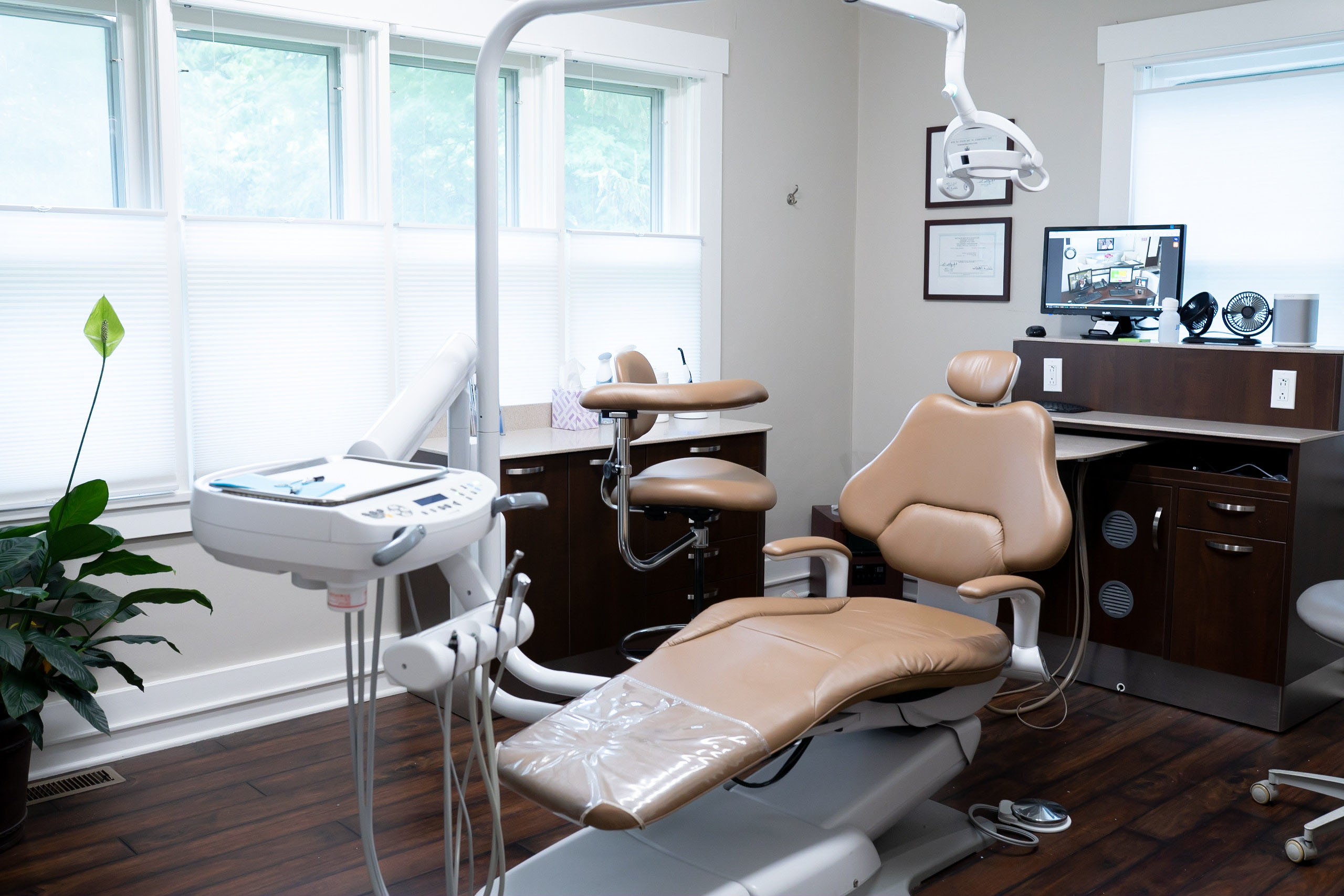 The image displays a well-equipped dental office with multiple dental chairs, a reception desk, and various dental equipment.
