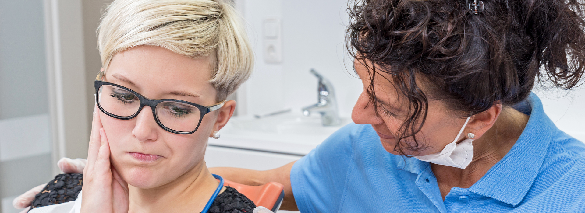 The image shows a dental hygienist assisting a patient during a teeth cleaning appointment.