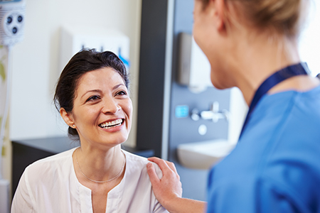 The image shows two individuals in a medical setting  a woman wearing a white coat stands beside a man with a stethoscope around his neck, both smiling at each other.