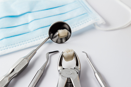 The image displays a collection of dental instruments placed on a white surface with a blue cloth underneath, showcasing the tools used in dental procedures.