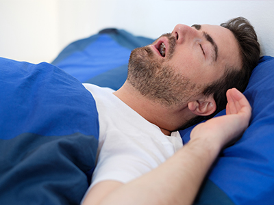 Man sleeping peacefully in bed with blue sheets.