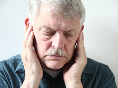 The image features a split-screen comparison of an elderly man's face with his hands placed on either side of his head, one hand on each ear, suggesting discomfort or pain.